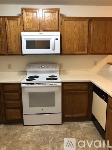 A white stove and microwave in a kitchen with wooden cabinets.