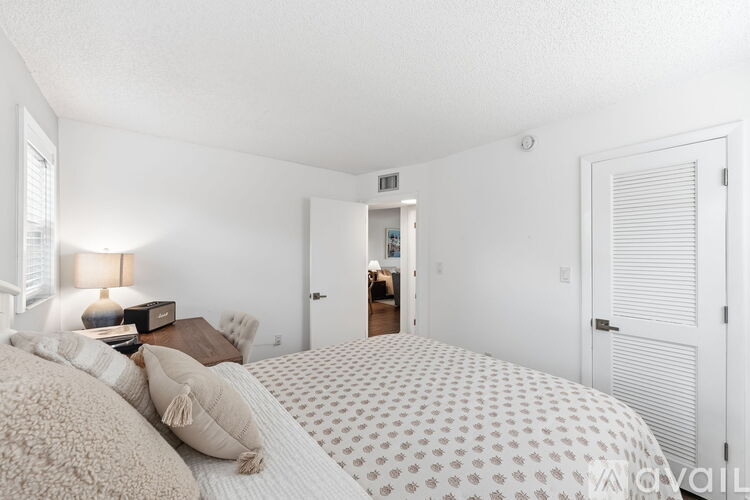 A bedroom with a large bed and a lamp on a side table.