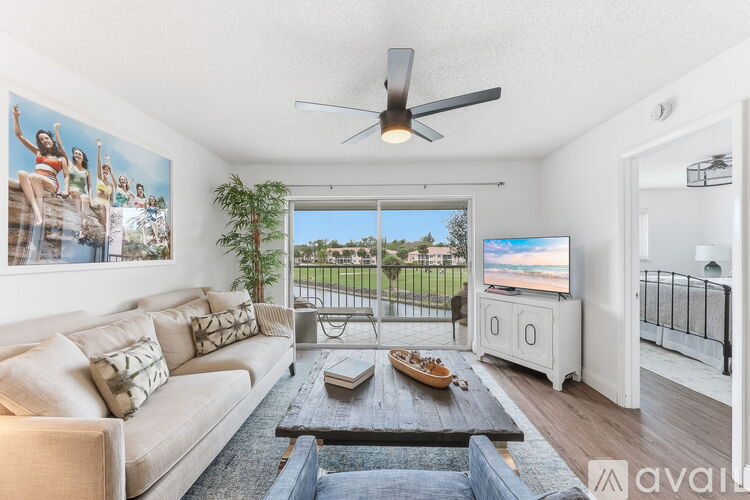 A living room with a couch, a coffee table, a television, and a painting on the wall.