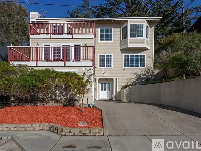 A two-story house with a red front yard and a white door.