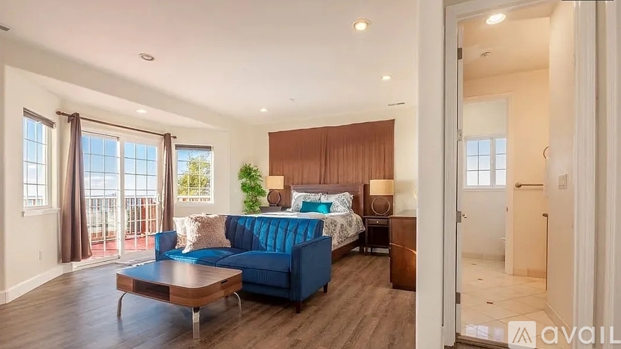 A bedroom with a blue couch and a wooden headboard.