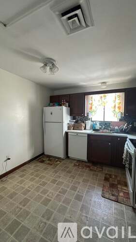 A kitchen with a refrigerator, sink, and a window.