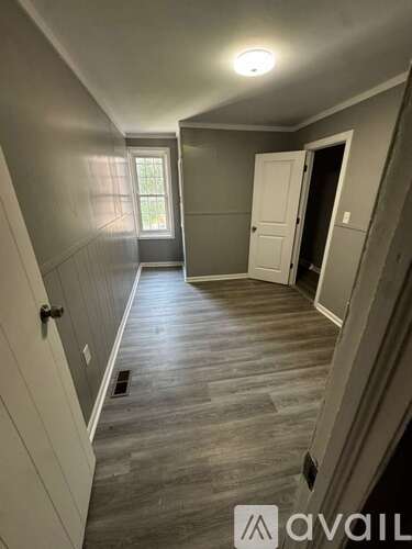 A hallway with a wooden floor and white walls.