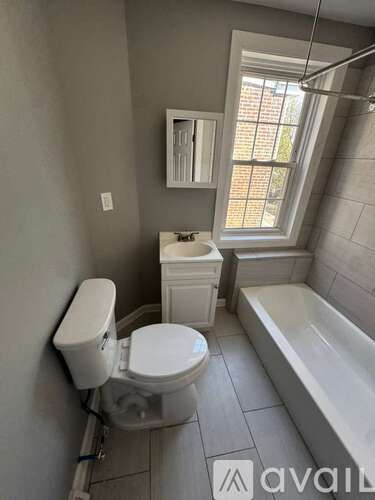 A bathroom with a toilet, tub, and window.