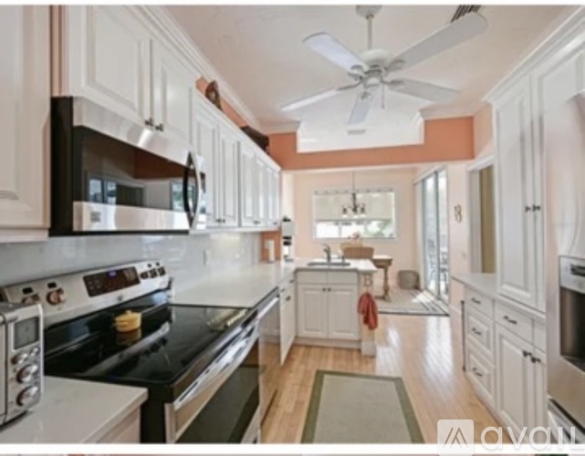 A kitchen with white cabinets and black appliances.