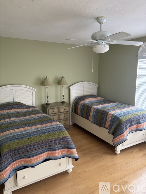 A bedroom with two beds and a ceiling fan.