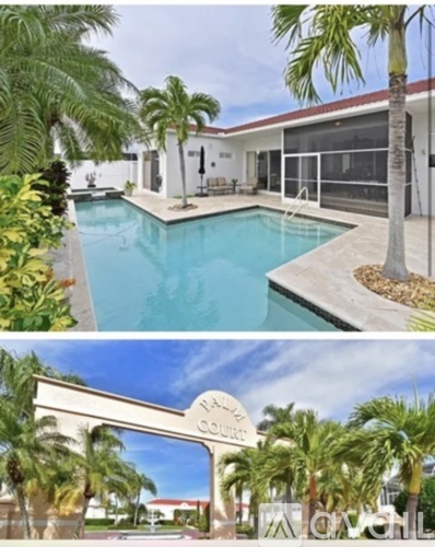 A pool and a house surrounded by palm trees.