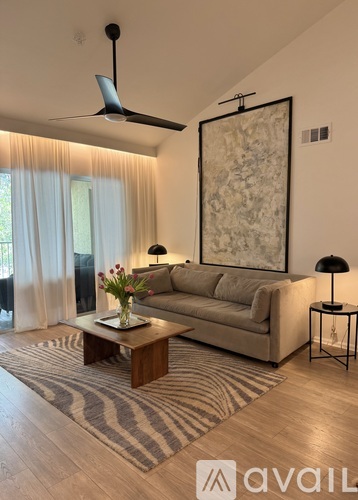 A living room with a beige couch, a coffee table, and a large painting on the wall.