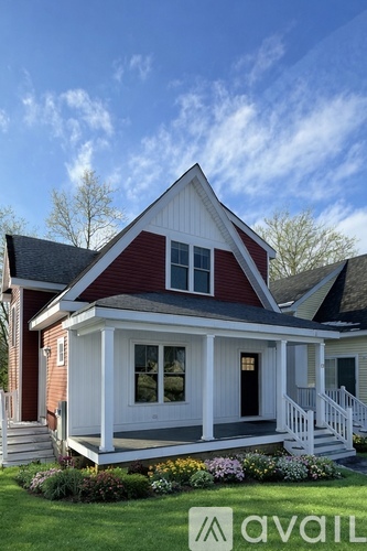 A house with a red roof and white trim is for sale.