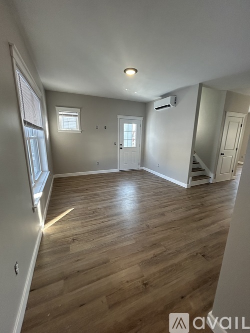 A spacious room with wooden flooring and a window.