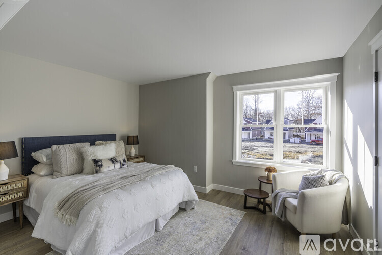 A bedroom with a large bed and a chair by the window.