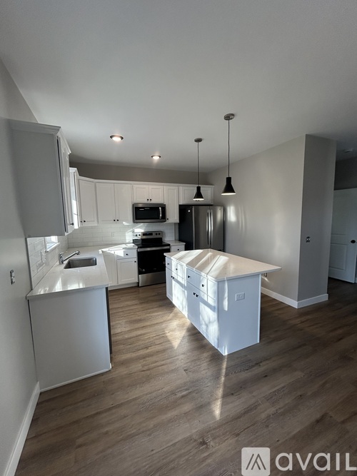 A kitchen with white cabinets and a wooden floor.