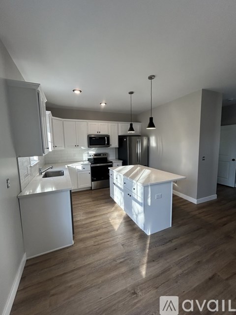 A kitchen with white cabinets and a wooden floor.