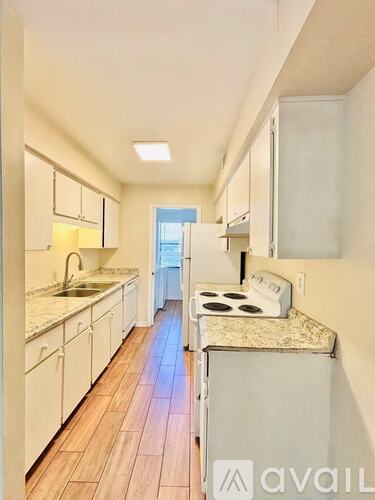 A kitchen with white cabinets and a wooden floor.