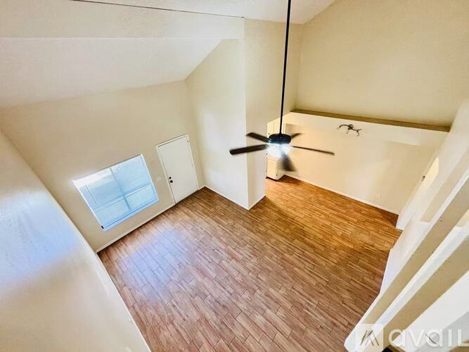A room with a ceiling fan and wooden flooring.