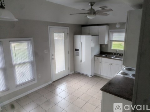 A kitchen with white appliances and a fan.