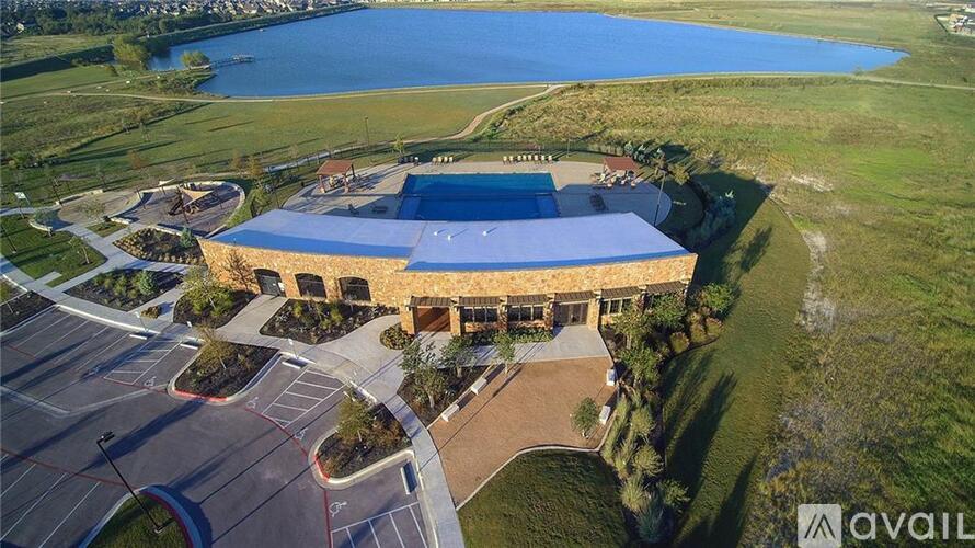 A large building with a blue roof is surrounded by a parking lot and a body of water.