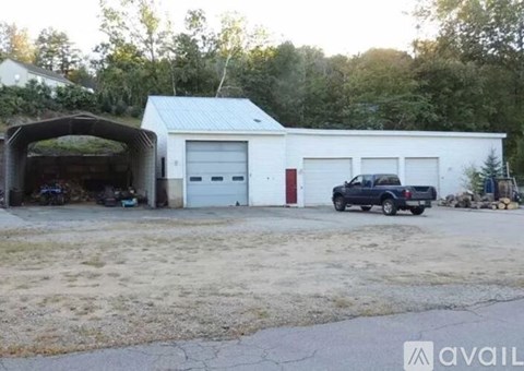 A black truck is parked in front of a white garage with a red stripe on the door.