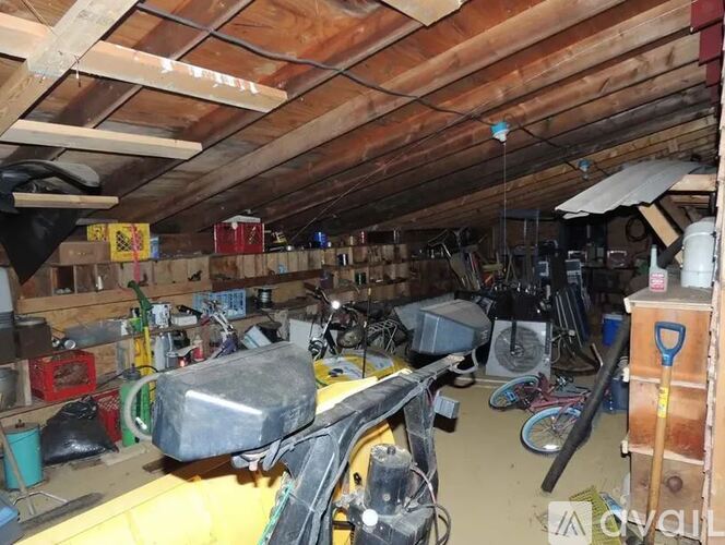A cluttered garage with a variety of items including a bicycle, a toolbox, and a workbench.