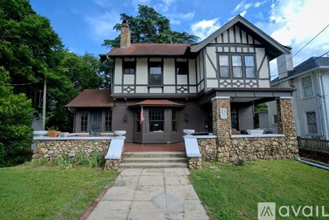 A house with a stone wall and a brown roof.