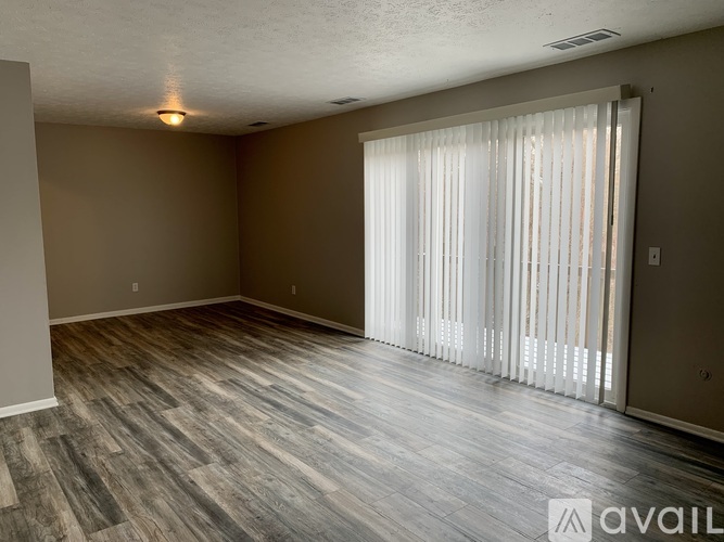 A room with wooden flooring and a sliding door with blinds.