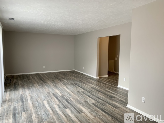 A room with wooden flooring and a door on the right side.