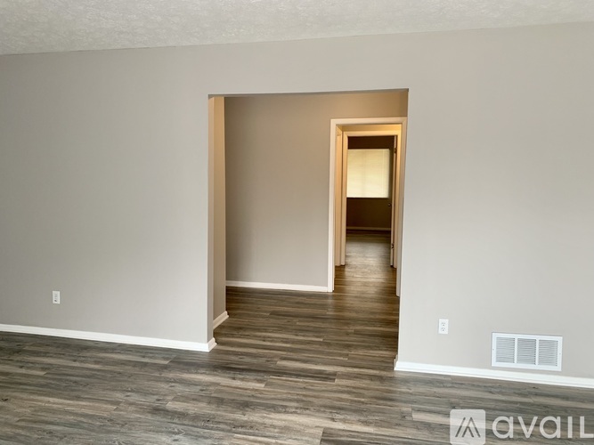 A room with a wooden floor and a doorway leading to another room.