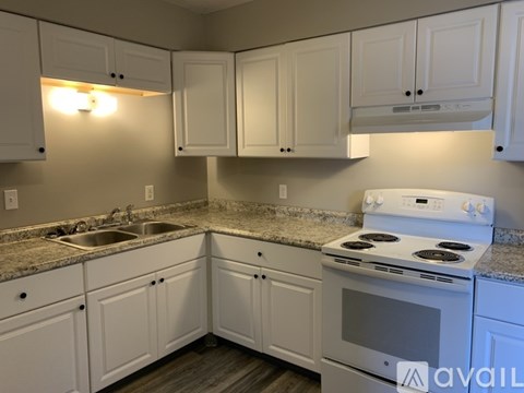 A kitchen with white cabinets and a white stove top oven.