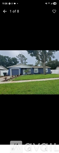 A blue house with a white roof and a tree in front.
