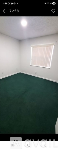 A room with a green floor and a window with white blinds.