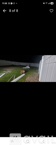 A dog is sitting on the grass in front of a building.