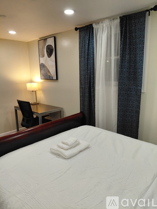 A bedroom with a bed, desk, chair, and a picture on the wall.