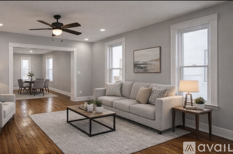 A living room with a grey couch, a coffee table, and a ceiling fan.
