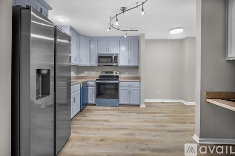 A kitchen with a refrigerator on the left and a microwave above the stove.