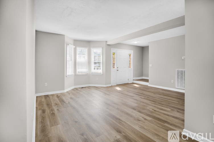 A spacious room with wooden flooring and white walls.