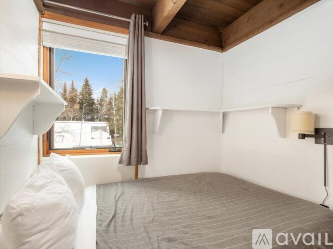 A bedroom with a large bed and a window overlooking a snowy landscape.