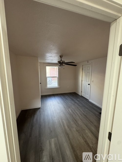 A room with a ceiling fan and wooden flooring.