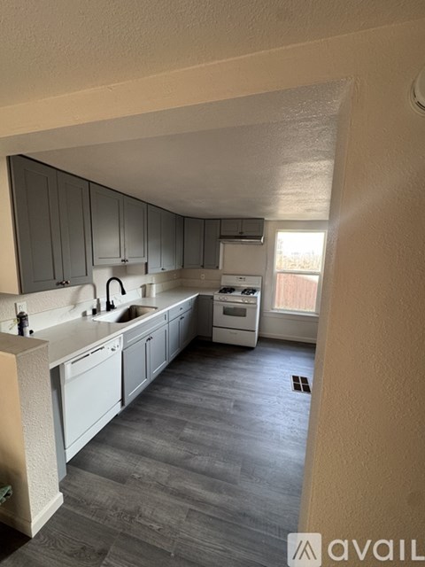 A kitchen with grey cabinets and a white countertop.