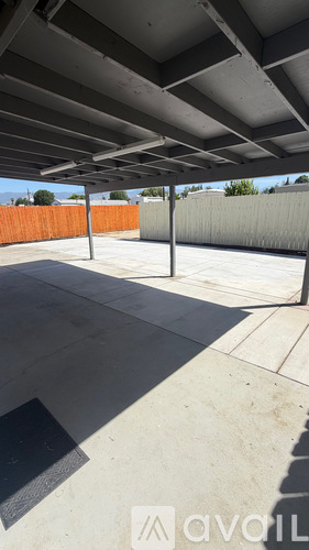 A concrete patio with a metal roof and a concrete pillar.