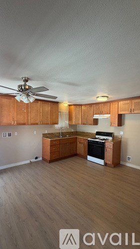A kitchen with wooden cabinets and a fan on the ceiling.