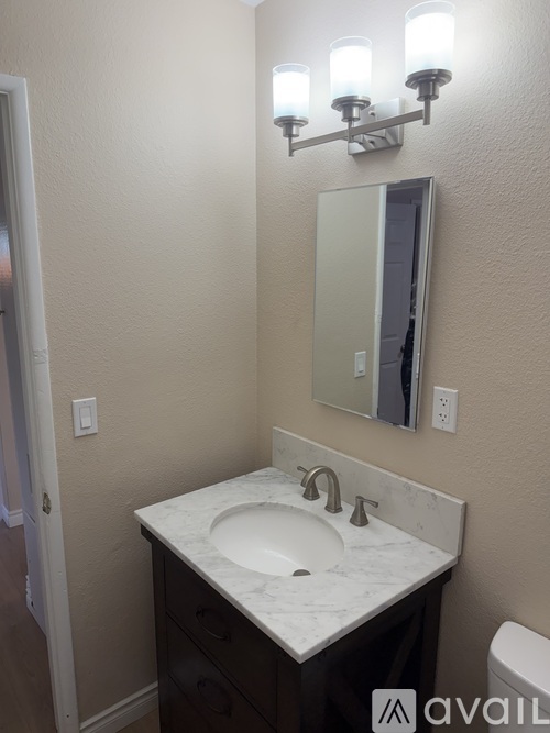 A bathroom with a sink, mirror, and light fixture.