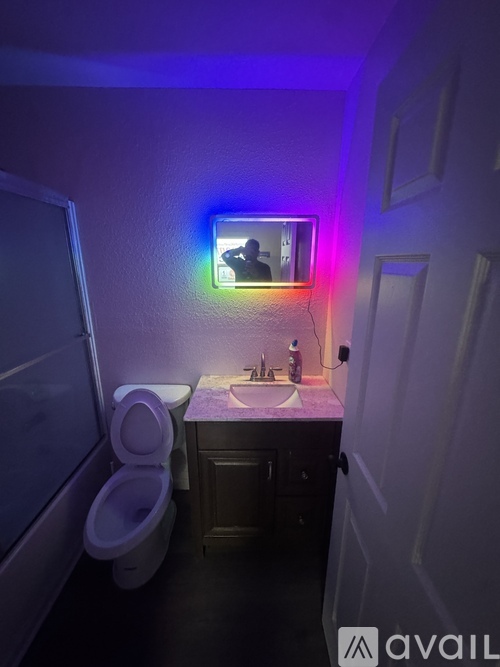 A bathroom with a toilet, sink, and mirror.