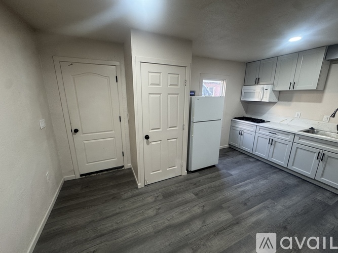 A kitchen with white cabinets and a grey floor.
