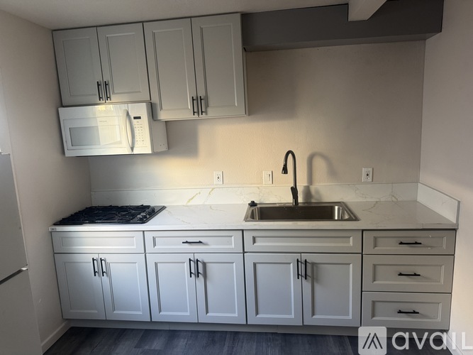 A kitchen with white cabinets and a stainless steel sink.