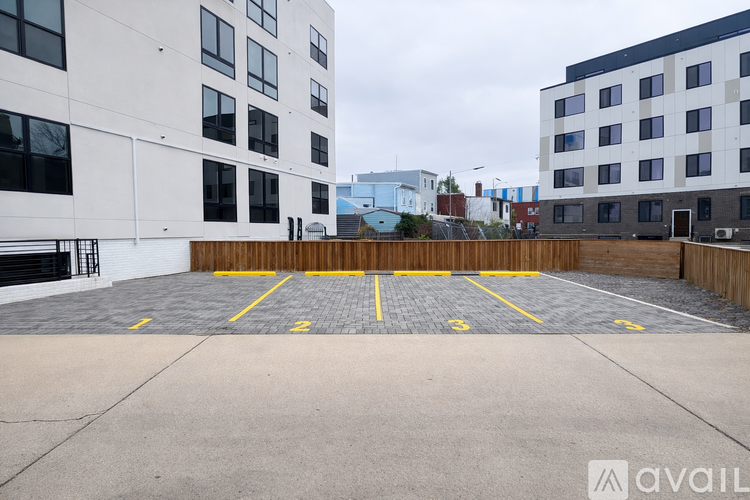 A parking lot with yellow lines and a building in the background.