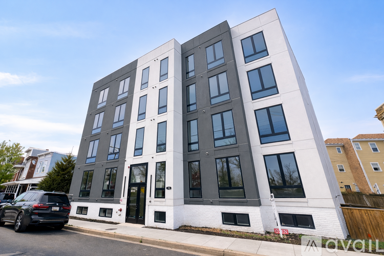 A modern multi-story building with a white facade and dark windows.