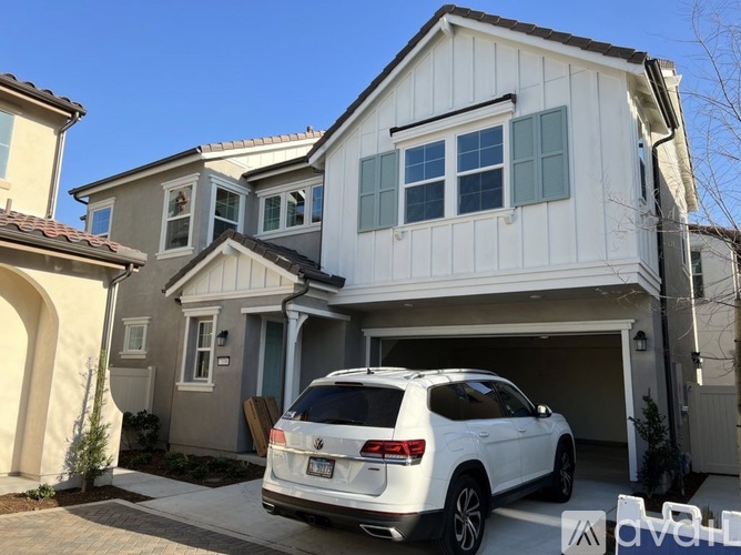A white SUV is parked in front of a two-story house.