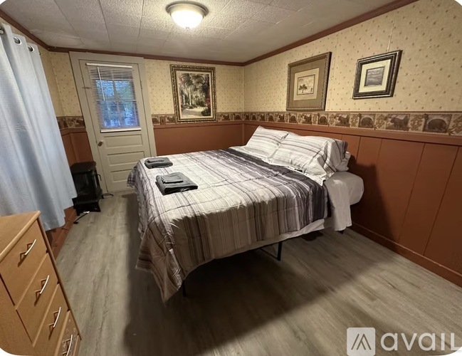 A bedroom with a bed, nightstand, and a window.