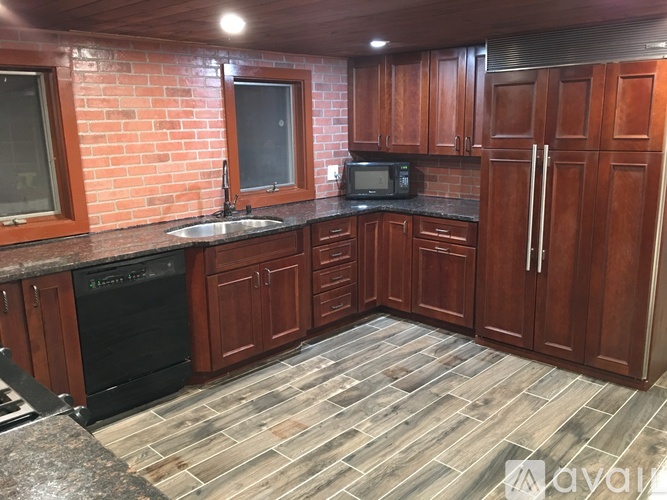 A kitchen with wooden cabinets and a brick wall.