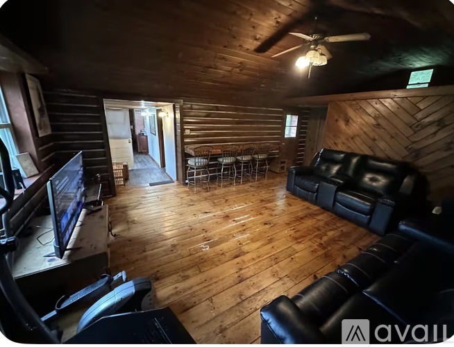 A living room with a black leather couch and a wooden floor.